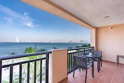 a balcony with a table and chairs and the ocean at Burj & Sea View King 2 Bedroom Apartment In Anantara Resort in Dubai