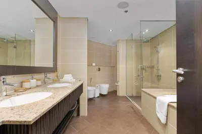 a bathroom with two sinks and a shower and two toilets at Burj & Sea View King 2 Bedroom Apartment In Anantara Resort in Dubai