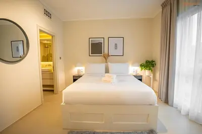 a white bedroom with a white bed and a mirror at Bnbeyond's Luxury Vibe & Burj View in Dubai