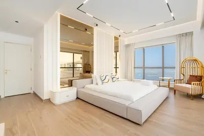 a white bedroom with a large white bed with a view of the ocean at King 2 Bedroom Jumeirah Beach & Dubai Eye Views in Dubai