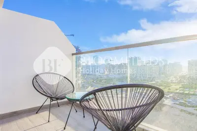 a balcony with two chairs and a table in front of a window at Bloomfields Charming Stu in Samana View in Dubai