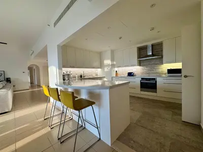 a kitchen with white cabinets and yellow bar stools at Large 5-BR JBR Apartment, Perfect for Families, Easy Beach Access in Dubai