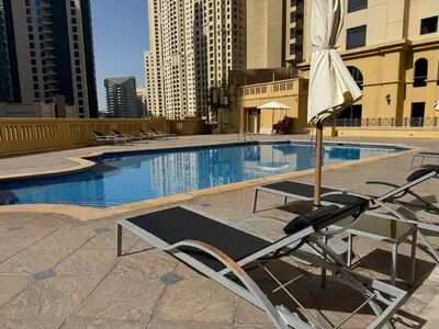 a swimming pool with a chair next to a swimming pool at Large 5-BR JBR Apartment, Perfect for Families, Easy Beach Access in Dubai