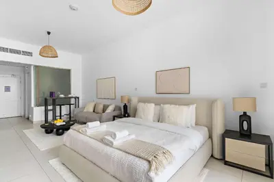 a white bedroom with a large bed and a couch at Silkhaus Seaside Studio in Palm Views West Tower in Dubai