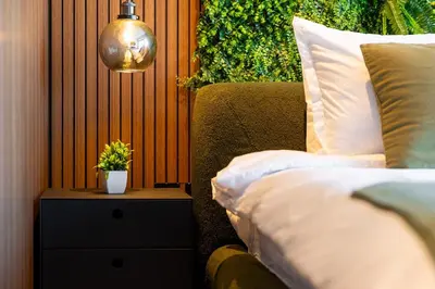 a bedroom with a bed and a night stand with a plant at Waves - Tranquil Waterfront Living 2B Retreat With Balcony in Dubai