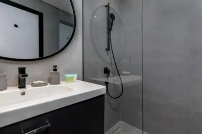 a bathroom with a sink and a shower with a mirror at Waves - Tranquil Waterfront Living 2B Retreat With Balcony in Dubai