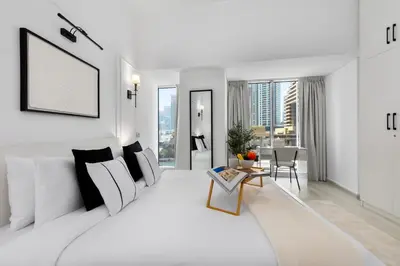 a white bedroom with a large bed and a living room at Maison Privee - Sleek Stay in Dubai Marina Famous Twisting Tower in Dubai