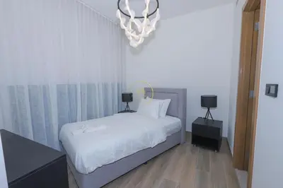 a bedroom with a bed with white sheets and a chandelier at Sobha Hartland Waves-912 in Dubai