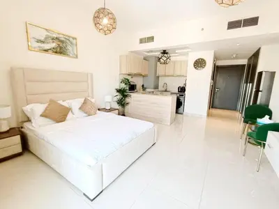 a white bedroom with a large bed and a kitchen at SUPERIOR STAY HOLIDAY HOMES - Sleek & Modern Studio in Business Bay in Dubai