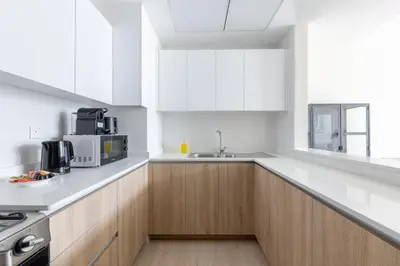 a white kitchen with wooden cabinets and a sink at Canal View, Partial Burj Khalifa View in Dubai