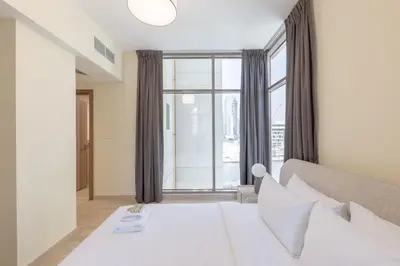 a bedroom with a white bed and a large window at Premium Apartment, Right Infront of Canal in Dubai