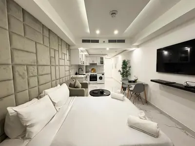 a bedroom with a large white bed and a kitchen at Modern & Stylish Studio Retreat in Dubai