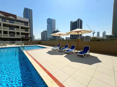 a pool with chairs and umbrellas on a building at Modern & Stylish Studio Retreat in Dubai