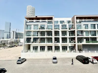 a large building with cars parked in a parking lot at Homes2Retreat - Very Spacious Studio in the Heart of JVC in Dubai