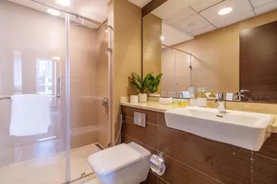 a bathroom with a sink and a toilet and a mirror at Luxurious 2Bed in Sparkle Tower-Marina View in Dubai