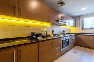 a kitchen with wooden cabinets and a stove top oven at Luxurious 2Bed in Sparkle Tower-Marina View in Dubai