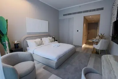 a bedroom with a bed and two chairs and a table at Modern Studio in Condor Concept7, JVC in Dubai