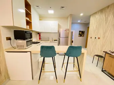 a kitchen with two blue chairs at a counter at Dubai Luxury Apartments In a good place in Dubai