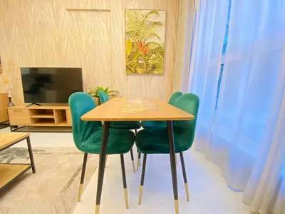 a dining room with a wooden table and green chairs at Dubai Luxury Apartments In a good place in Dubai
