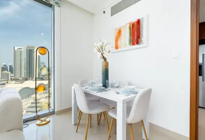 a dining room with a white table and chairs and a window at King 2BR With Burj Khalifa View In Boulevard Point in Dubai
