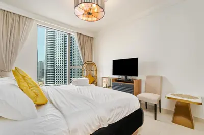 a white bedroom with a large bed and a television at King 2BR With Burj Khalifa View In Boulevard Point in Dubai