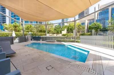 an outdoor swimming pool with an umbrella over it at King 2BR With Burj Khalifa View In Boulevard Point in Dubai