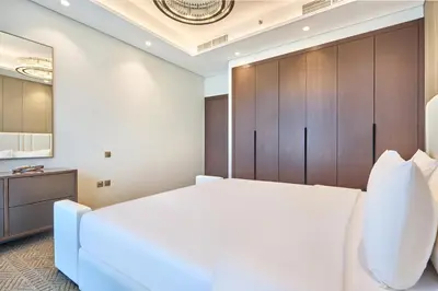 a bedroom with a large white bed and wooden cabinets at Two Bedroom Apartment in Nobles Tower by The S Holiday Homes in Dubai