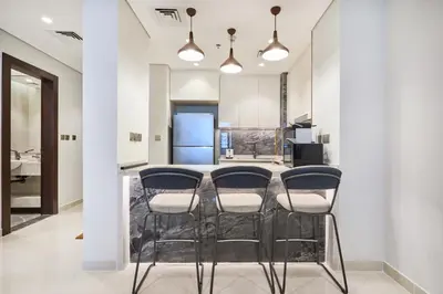 a kitchen with a bar with four stools at Two Bedroom Apartment in Nobles Tower by The S Holiday Homes in Dubai