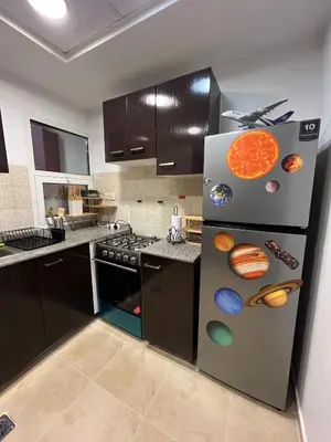 a kitchen with a refrigerator with planets on it at New 1BED Apartment in Remraam, Dubai Land, Motor city, Damac hills, Mudoon area in Dubai