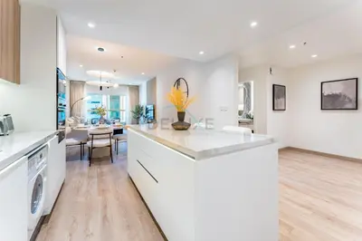 a kitchen with white cabinets and a dining room at Renovated 1BR with Partial Sea and City Views Near Beach, Elite Residence, Dubai Marina by Deluxe Holiday Homes in Dubai