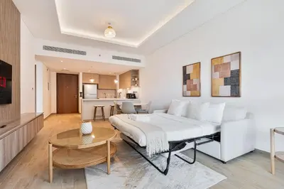 a bedroom with a large bed and a living room at Chic 1BR APT with Pool, Gym & Kid's Playground in Dubai