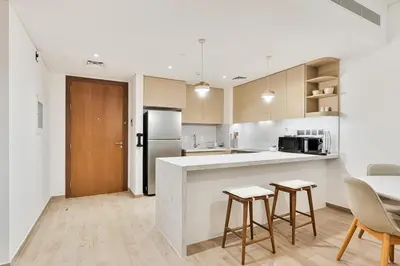 a kitchen with a counter and chairs and a refrigerator at Chic 1BR APT with Pool, Gym & Kid's Playground in Dubai