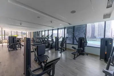 a gym with rows of treadmills and elliptical machines at Casa Tranquila Luxury Suites with Burj Khalifa & Canal Views in Dubai