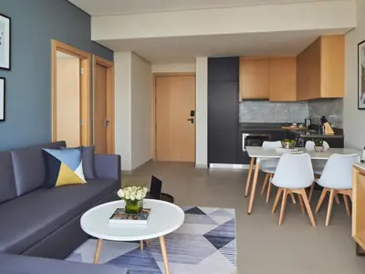 a living room with a couch and tables and a kitchen at Private Apartment in Novotel JVT Comfort for 4 Guests in Dubai