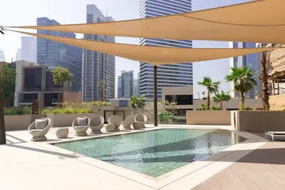 a swimming pool with chaise lounge chairs and an umbrella at Stunning Studio in Peninsula Five in Dubai