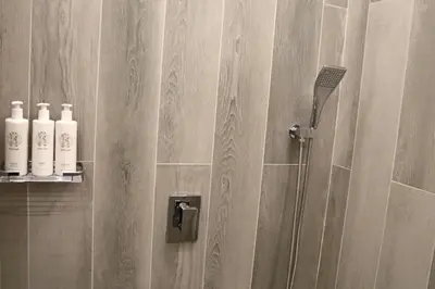 a bathroom with a shower with white bottles on the wall at Casa Royale Vacation Home - JVC in Dubai