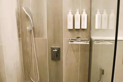 a bathroom with a shower with white bottles on the wall at Casa Royale Vacation Home - JVC in Dubai