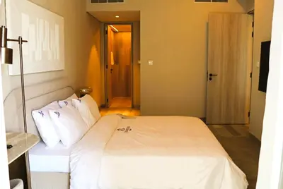 a bedroom with a bed with white sheets and pillows at Casa Royale Vacation Home - JVC in Dubai