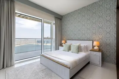 a bedroom with a bed and a large window at Maison Privee - Waterfront Living with Unparalleled Sea & Palm Vws in Dubai
