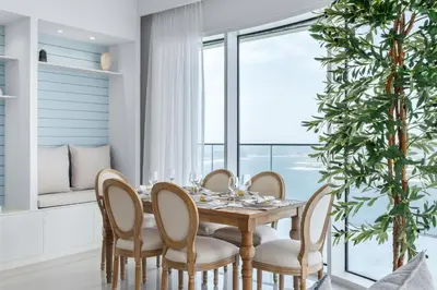 a dining room with a table and chairs and a large window at Maison Privee - Waterfront Living with Unparalleled Sea & Palm Vws in Dubai
