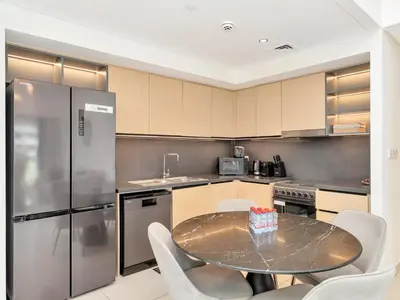 a kitchen with a table and chairs and a refrigerator at Stylish 3BR in BurjCrown Balcony & HighEnd Comfort in Dubai