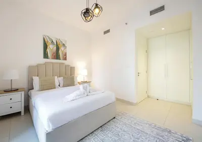 a white bedroom with a large white bed and a table at Upscale2BR in Burj Crown Pool,Gym & Stunning Views in Dubai