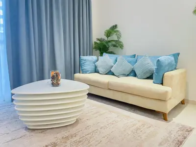 a living room with a couch with blue pillows at Vserve Comfy & Relaxing 1 BDR Retreat At the Palm in Dubai