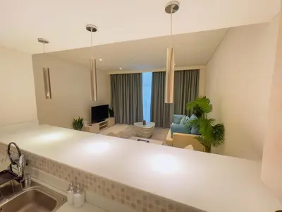 a kitchen with a sink and a living room at Vserve Comfy & Relaxing 1 BDR Retreat At the Palm in Dubai