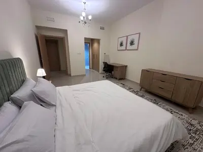 a bedroom with a large white bed and a desk at Spacious 1BR Apartment with Balcony in JVC - JLiving in Dubai