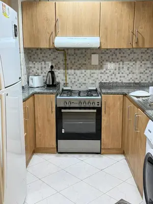 a kitchen with a stove and a refrigerator at Spacious 1BR Apartment with Balcony in JVC - JLiving in Dubai