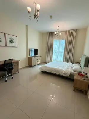 a bedroom with a bed and a desk and a tv at Spacious 1BR Apartment with Balcony in JVC - JLiving in Dubai