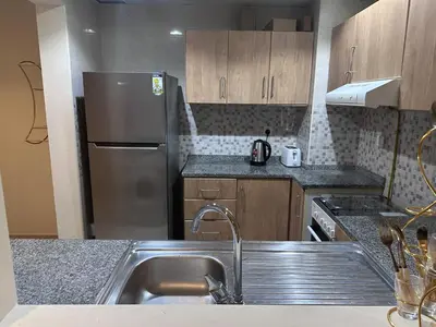 a kitchen with a sink and a stainless steel refrigerator at Spacious 1BR Apartment with Balcony in JVC - JLiving in Dubai