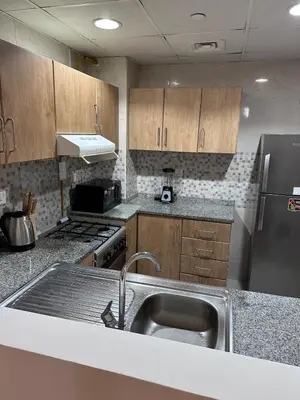 a kitchen with a sink and a stainless steel refrigerator at Large 1BR Apartment with Balcony in JVC - JLiving in Dubai