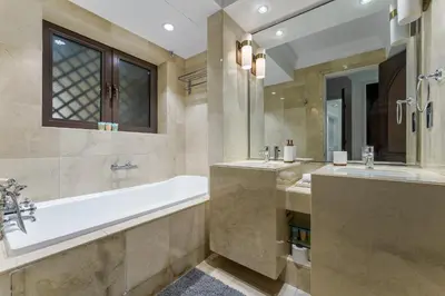 a bathroom with two sinks and a bath tub at Souk Al Bahar Luxury stays near poolside with Burj Khalifa view by Norbu Holiday Homes in Dubai